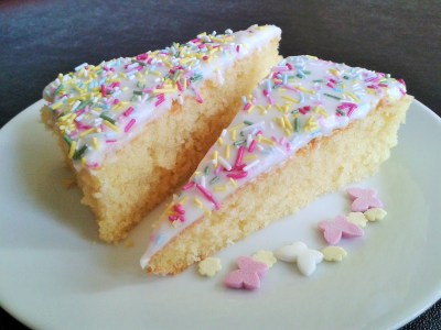 Old school sponge cake with white icing and multicoloured sprinkes